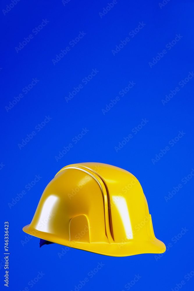 Fototapeta premium Hard hat for Labour Day concept, 3d render. Yellow helmet isolated on blue vertical background with copy space.