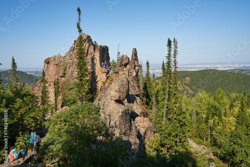 Large granite rock surrounded by green forest. Walking tourists. recreation, sport place at summer day. Active lifestyle climbing training, hiking near city. Power of Siberia. unusual nature landscape