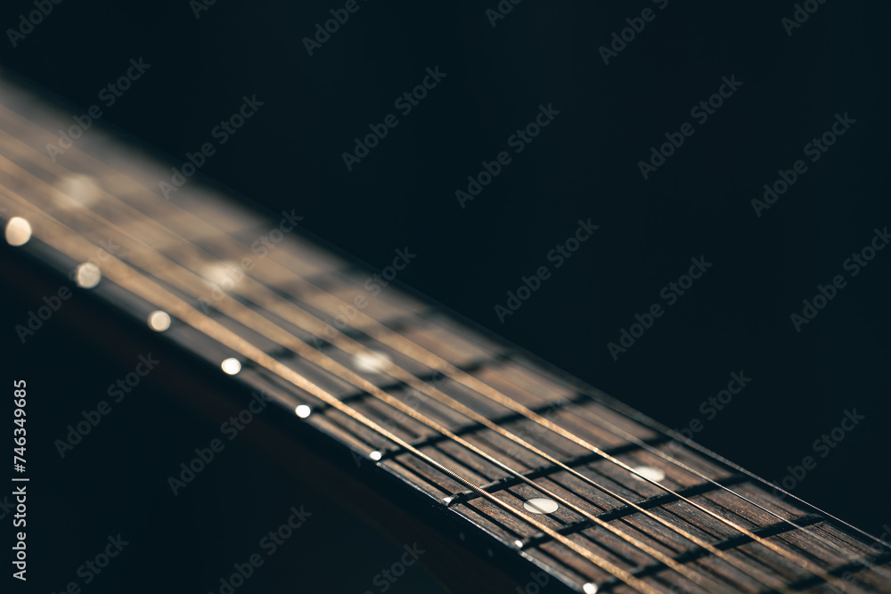 Fototapeta premium Part of an acoustic guitar, guitar fretboard on a black background.