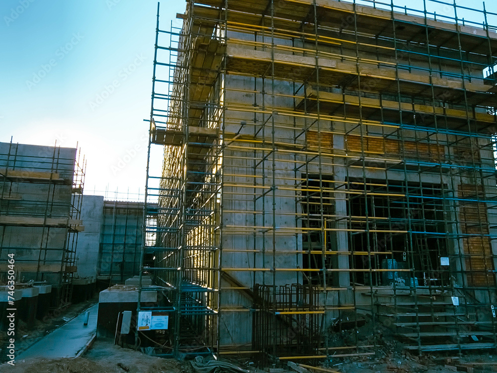 construction site with scaffolding and building materials, blue sky background