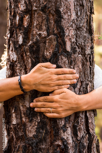 People hugging tree close up nature lover concept lifestyle image - one woman behing a trunk embracing and protect forest woods plant against deforestation. Environmental life outdoor leisure person