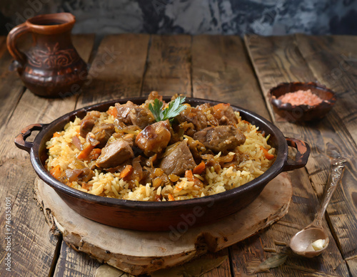 pilaf with meat and vegetables in a pan on a wooden table with rustic pottery vessels