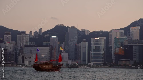 Wooden Junk boat sailing across Victoria Harbour with the Hong Kong skyline behind during sunset. Hong Kong. Hong Kong is one of the most densely populated city.