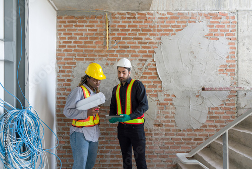 Obraz na plátně Two construction workers checking work schedule on tablet computer