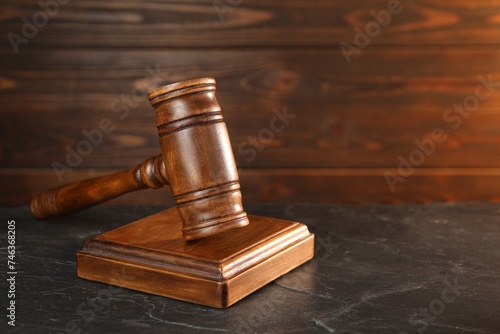 Wooden gavel and sound block on dark textured table, closeup. Space for text