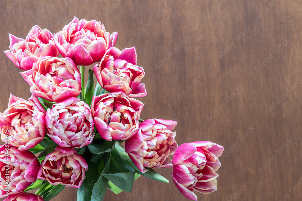 Pink fresh tulips on a wooden table, top view.