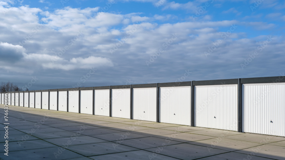 A row of garages or storage units on an industrial site under a sky with large dark clouds