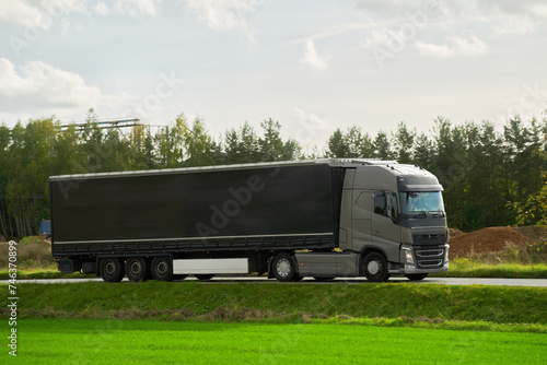 Delivery and shipping of goods by semitrailer trucks. The trucks drive on the road with containers of cargo. Concept of sustainable and efficient transport system. Land logistics industry mock-up.