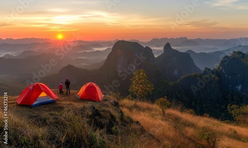 a serene morning scene with two tents set up on a mountain peak, as a person stands between them, gazing at the sunrise over a range of misty mountains and valleys.