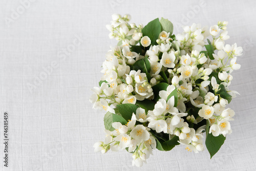 Bouquet of fresh delicate spring jasmine flowers on a linen tablecloth on the table. Top view, empty space. 