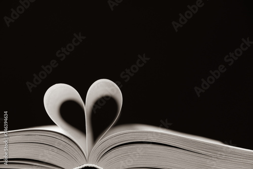 The pages of the book are folded in the shape of a heart on a black background, place for text