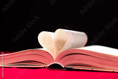 The pages of the book are folded in the shape of a heart on a pink and black background, place for text