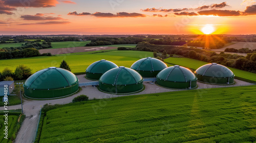 An aerial view of a farm with fields and buildings  set against a vibrant sunset in the background