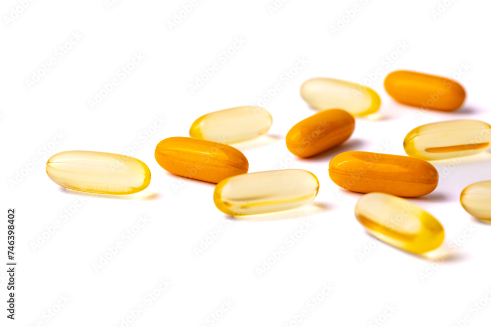Yellow and Orange Capsule Pills Scattered on a White Background Yellow and Orange Capsule Pills Scattered on a White Background