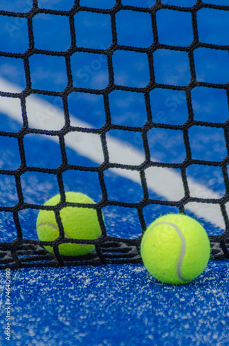 two paddle tennis balls close to the net of a paddle tennis court