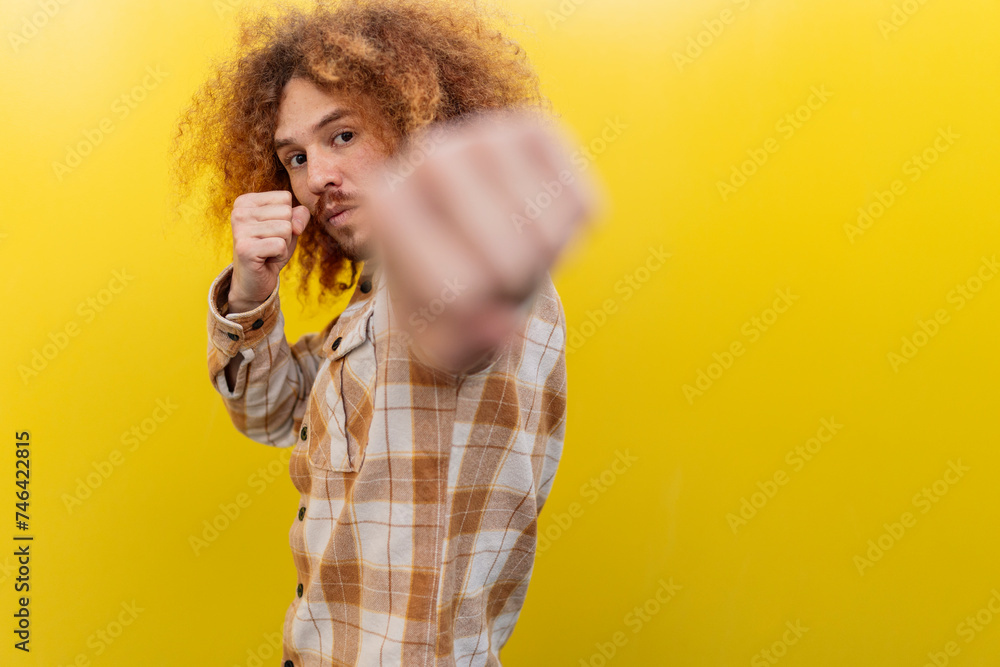 Man punching in front of yellow wall Man punching in front of yellow wall