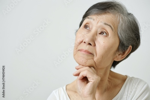 考えている日本人女性おばあちゃんのポートレート（白背景・検討中・思案・老後・年金・悩む）