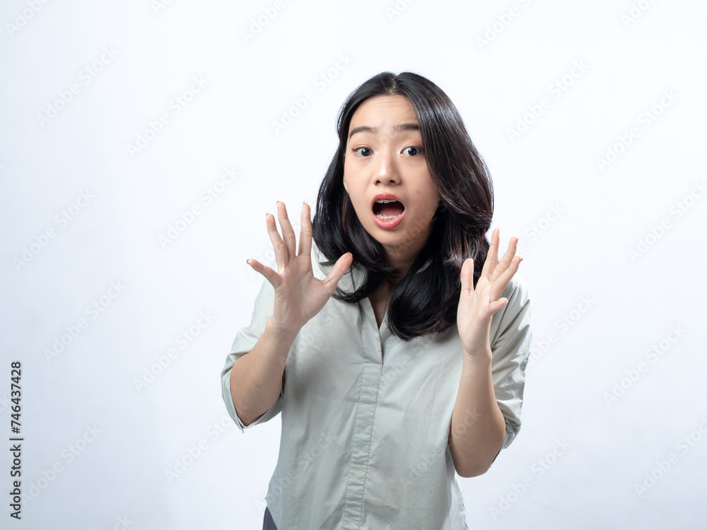 Shocked Asian woman with hands on cheeks, in a light gray blouse, against a plain white background Shocked Asian woman with hands on cheeks, in a light gray blouse, against a plain white background