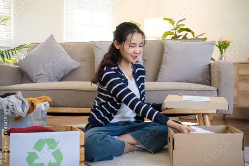 A young woman separates unused clothes and prepares them for donation or recycling in order to reduce air pollution and protect the environment.