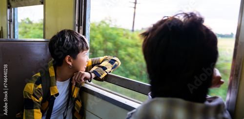 Happy Asian man and woman friends enjoy and fun outdoor lifestyle travel countryside by railroad transportation on summer holiday vacation. Generation z people sitting on train and talking together.