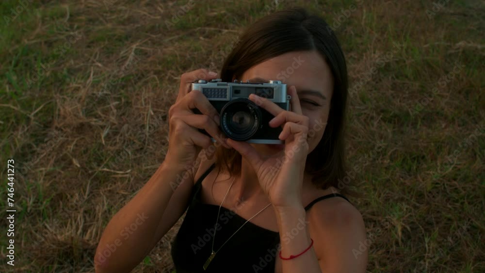 Portrait of a young woman with a retro camera in nature