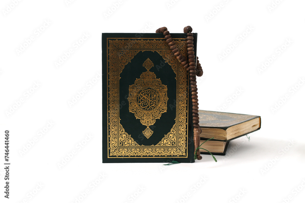The Holy Quran with Arabic calligraphy, meaning The Noble Quran, and a tasbih, isolated on a white background The Holy Quran with Arabic calligraphy, meaning The Noble Quran, and a tasbih, isolated on a white background