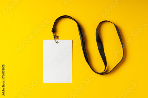 Blank nametag on a string on yellow background copy space