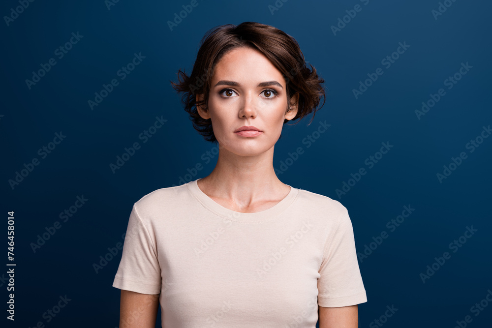 Photo portrait of charming young lady serious facial expression wearing beige pastel t-shirt isolated on dark blue color background Photo portrait of charming young lady serious facial expression wearing beige pastel t-shirt isolated on dark blue color background