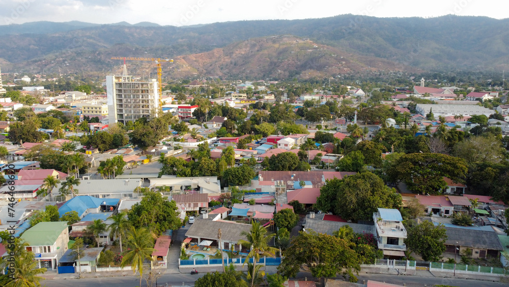 Aerial drone scenic view of the capital city of Dili, Timor-Leste in Southeast Asia with inner city houses, office buildings, green trees and hills  