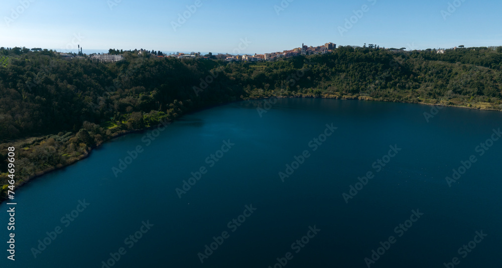 Aerial view of Lake Nemi. It is a small volcanic lake in the territory of the Castelli Romani. In background it is Genzano di Roma, a small town located in the Metropolitan City of Rome, Italy. 