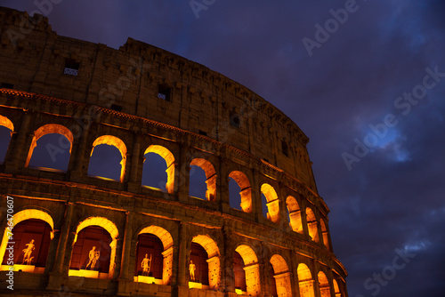 the wall of the colosseum with golden light at night in Rome, Italy