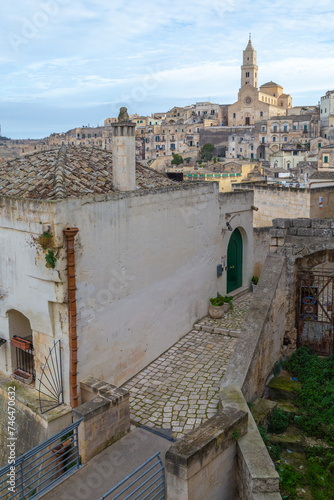 the narrow alley in Matera with ctheral of Maria Santissima della Bruna e Sant'Eustachio in the background, Italy  photo