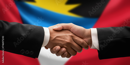 Businessman and diplomat in suits clasp hands for handshake over Antigua and Barbuda flag, agree on united success in trade, diplomacy, cooperation or negotiation, gesture of greeting