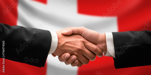 Businessman, diplomat in suits clasp hands for handshake over Switzerland flag, agree on united success in trade, diplomacy, cooperation, negotiation, teamwork in commerce, gesture of greeting