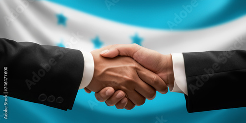 Businessman, diplomat in suits clasp hands for handshake over Honduras flag, agree on united success in trade, diplomacy, cooperation, negotiation, support, teamwork in commerce, gesture of greeting © Andrei