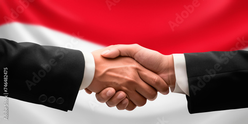 Businessman and diplomat in suits clasp hands for handshake over Monaco flag, agree on united success in trade, diplomacy, cooperation, negotiation, support, teamwork in commerce, gesture of greeting