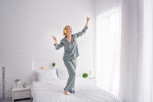 Photo portrait of blonde attractive young woman stand bed dancing dressed stylish gray pajama light modern bedroom minimalist design photo