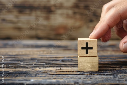 Hand placing wooden block with plus sign on wooden table, business, strategy concept. photo