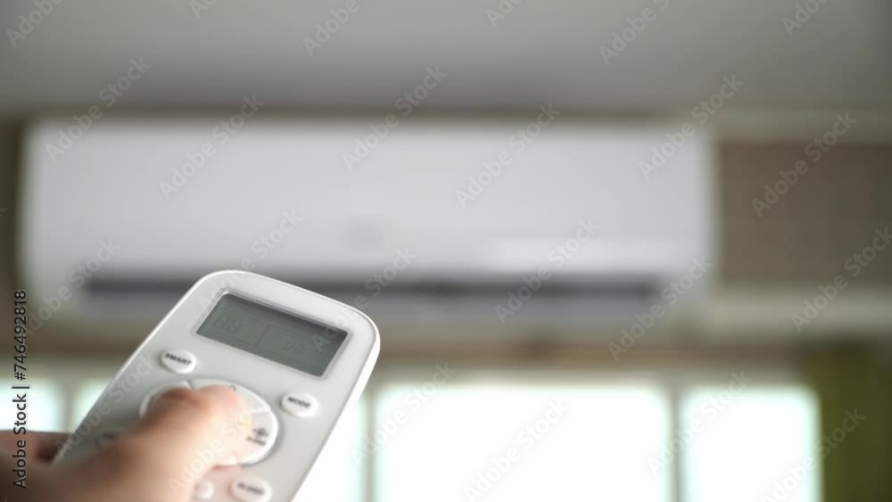 Man's hand using remote control open The air conditioner is cooled to 25 degrees Celsius in his bedroom. Man's hand using remote control open The air conditioner is cooled to 25 degrees Celsius in his bedroom.