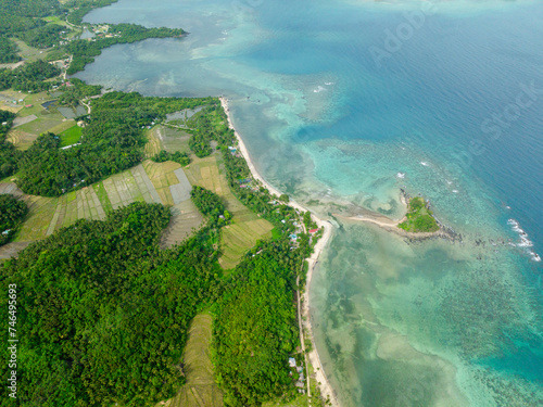 Top view of white sand beach with waves and farmlands in Santa Fe, Tablas, Romblon. Philippines.