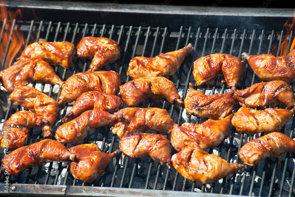 Spicy Marinated Chicken legs grilling on a summer barbecue .