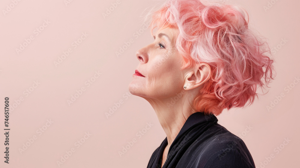 Profile of a senior woman with pink hair against pastel background. Profile of a senior woman with pink hair against pastel background.