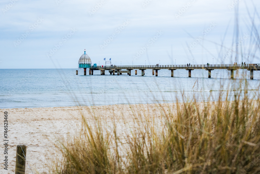 Pier at the baltic sea in Zinnowitz on an overcast day with dune grass and beach in the foreground