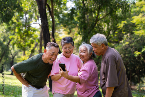 Group of happy Senior Retirement Using Smartphone and laughing outdoors at the park after a workout and spending time together, concepts about the elderly, seniority, and wellness aging © Prot