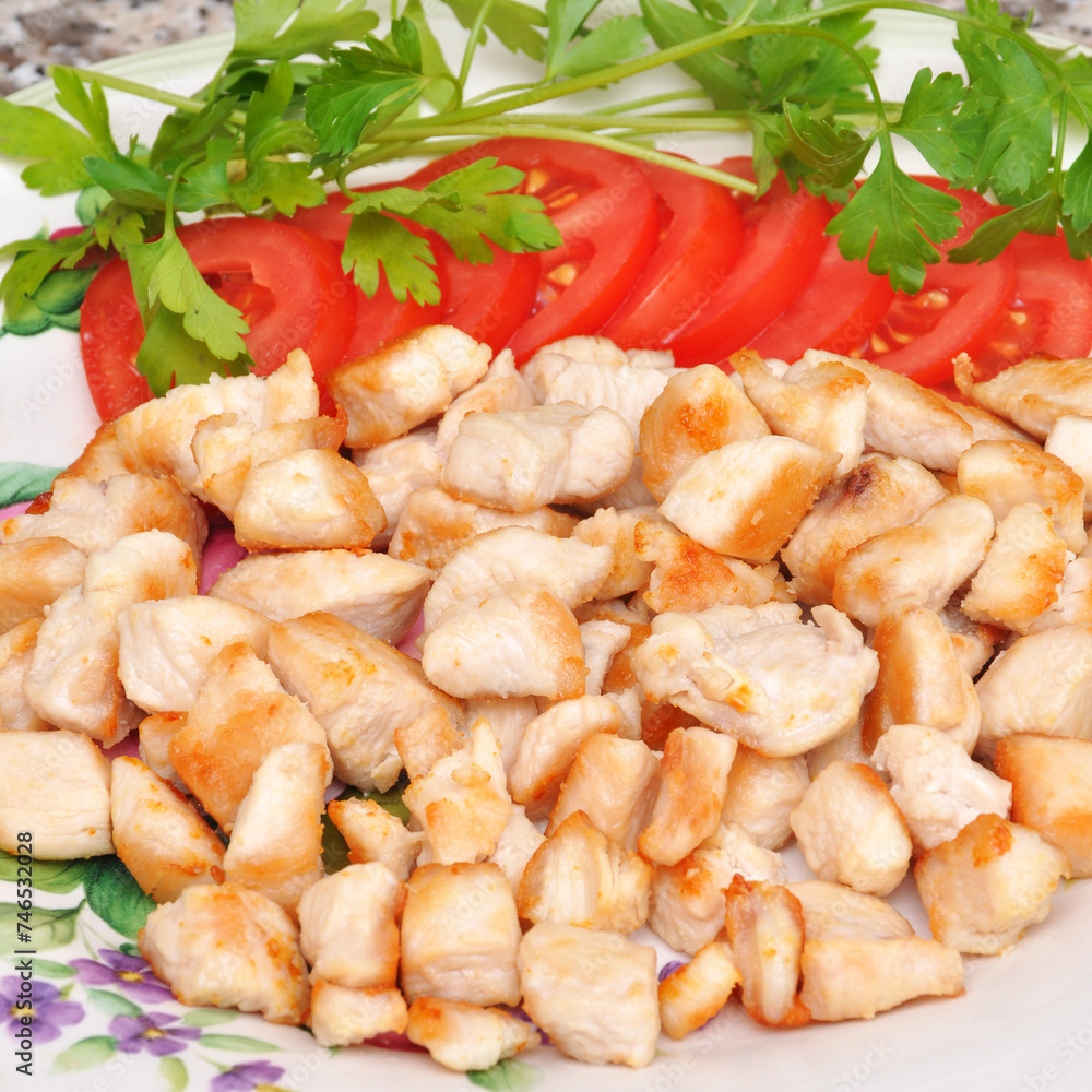 Fresh and fried chicken meat breast pieces, ready to cook, with tomato and parsley Fresh and fried chicken meat breast pieces, ready to cook, with tomato and parsley