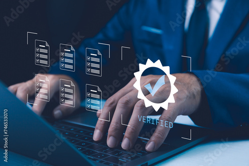 Photos Business professional verifying documents on a laptop, with a virtual 'Verified' stamp showcasing secure, authenticated processes