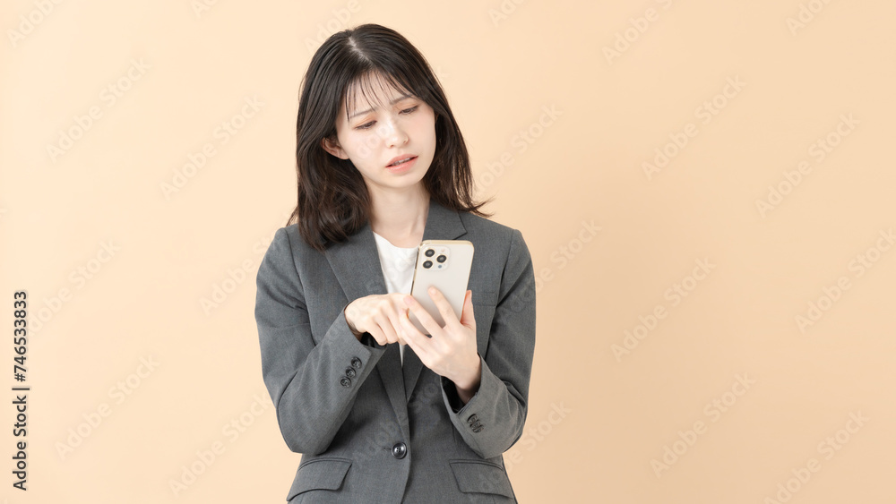 スマートフォンを見て悩む女性