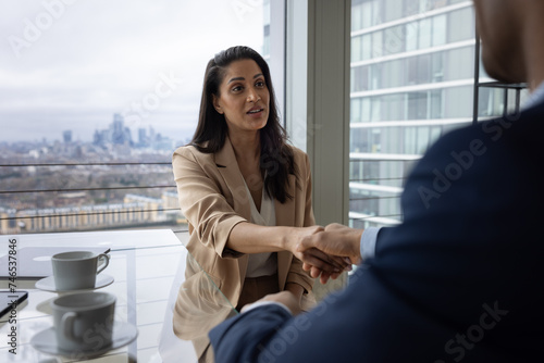 Businesswoman shaking hands in a corporate meeting with view of London city skyline photo