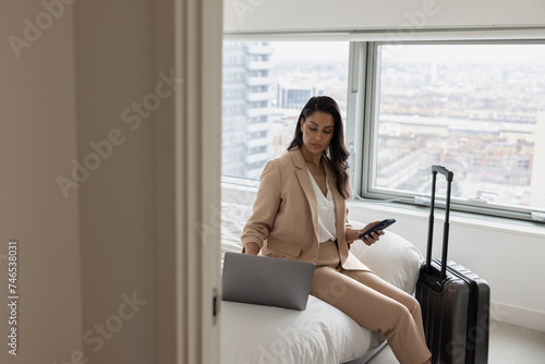 Business executive in hotel working using her cell phone photo