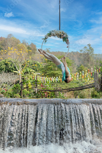 Beautiful Asian woman playing Rig and Hang Aerial Hook for Yoga in Nature scenery.